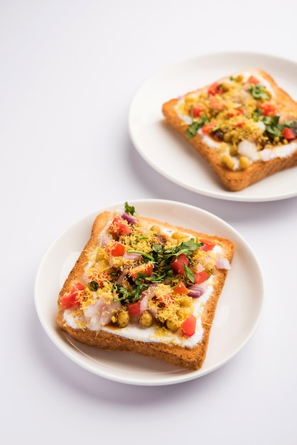 Dahi Bread papdi chaat, chat is a yummy starter or appetizer from India, served in a plate garnished with tomato, sev and coriander and masala. selective focus