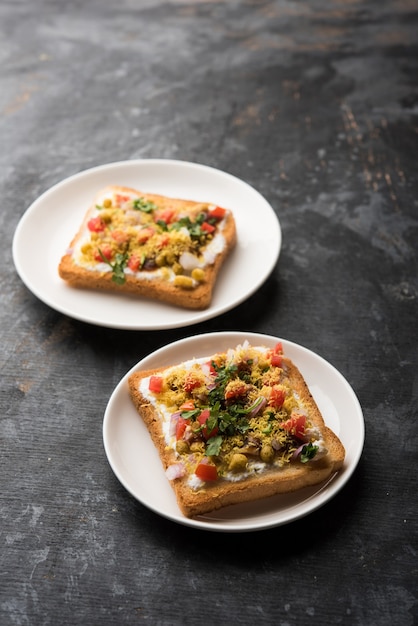 Dahi Bread papdi chaat, chat is a yummy starter or appetizer from India, served in a plate garnished with tomato, sev and coriander and masala. selective focus