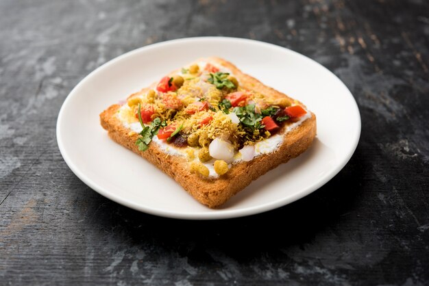 Dahi Bread papdi chaat, chat is a yummy starter or appetizer from India, served in a plate garnished with tomato, sev and coriander and masala. selective focus