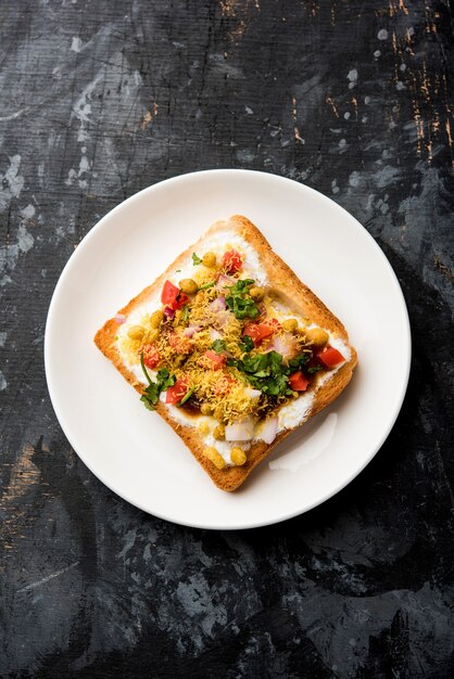 Dahi Bread papdi chaat, chat is a yummy starter or appetizer from India, served in a plate garnished with tomato, sev and coriander and masala. selective focus