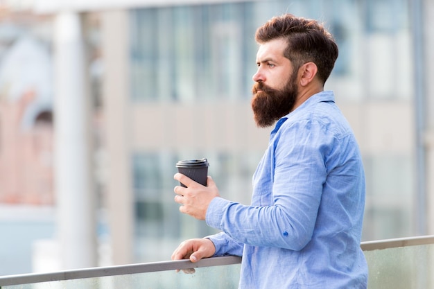 Daily rituals Morning coffee concept Caffeine energy charge Man drink take away coffee outdoors urban background Set up for new day Personal efficiency Guy bearded hipster enjoying coffee alone