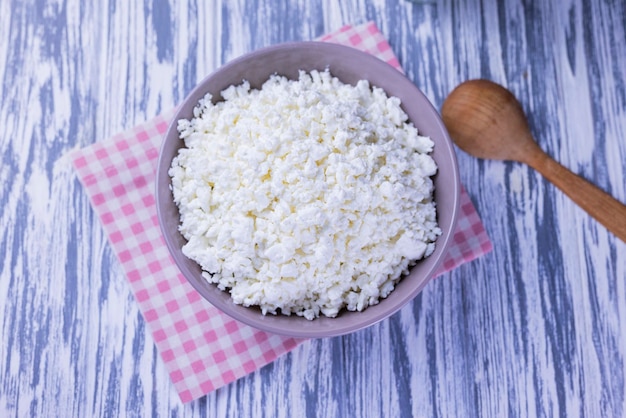 Dairy product cottage cheese in a plate on a wooden background