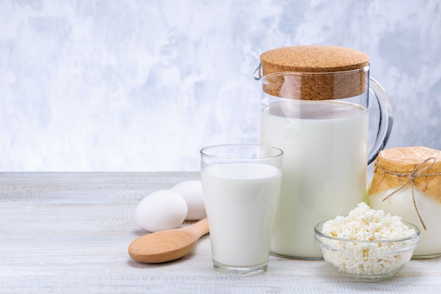 Dairy Products, Milk, Cottage Cheese, Eggs And Sour Cream On Wooden Table Against Grey Wall With Copy Space.