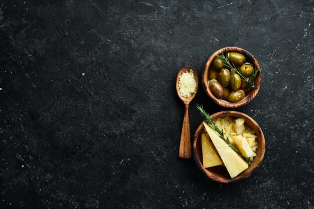 Dairy products Parmesan cheese olives and snacks on a stone table Top view On a concrete background