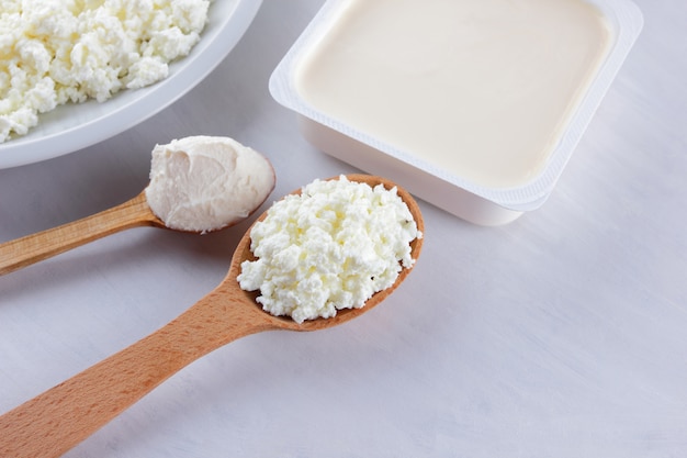 Dairy products on a white board. Cottage cheese, cream and soft cheese on a white background