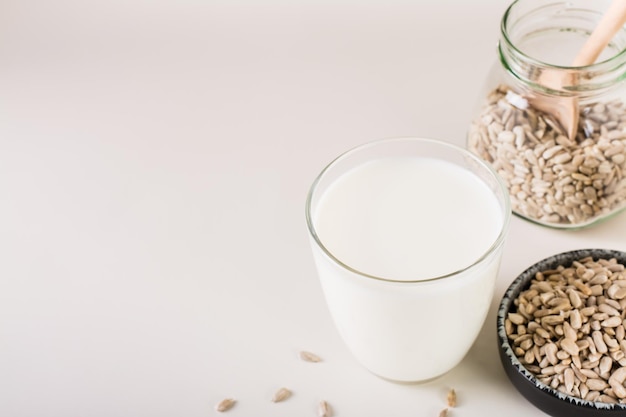 Dairyfree sunflower milk in a glass and seeds in a bowl on the table Healthy food