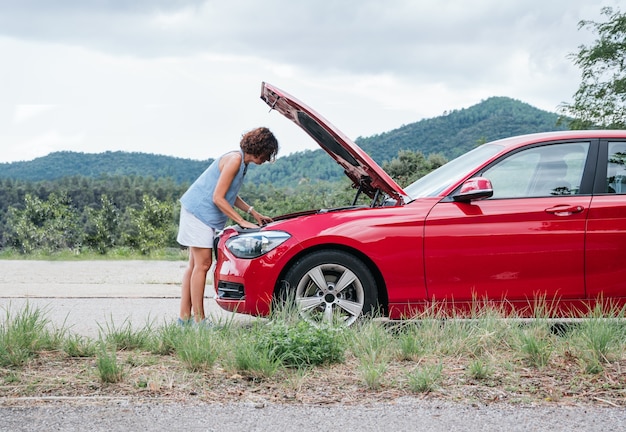 damaged car, woman looks at engine