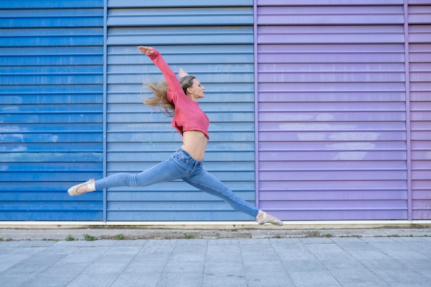 Dancer woman jumping in front of a colorful wall