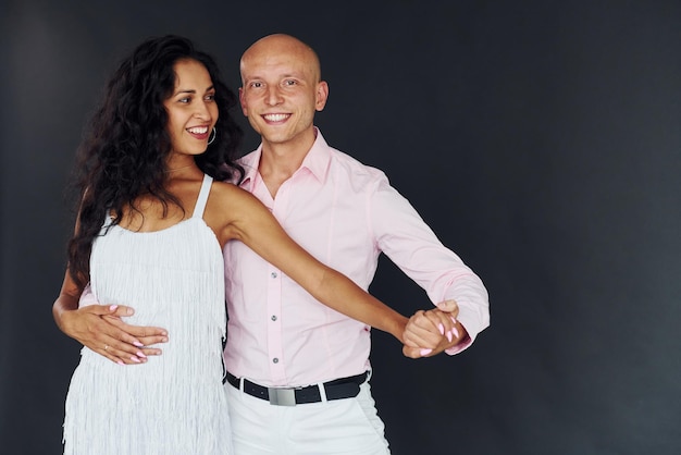 Dancing against black background Cheerful couple is together indoors