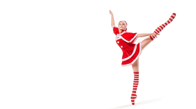 Dancing ballerina with a box of gifts in her hands on pointe shoes in Santa Claus costume isolated on white background