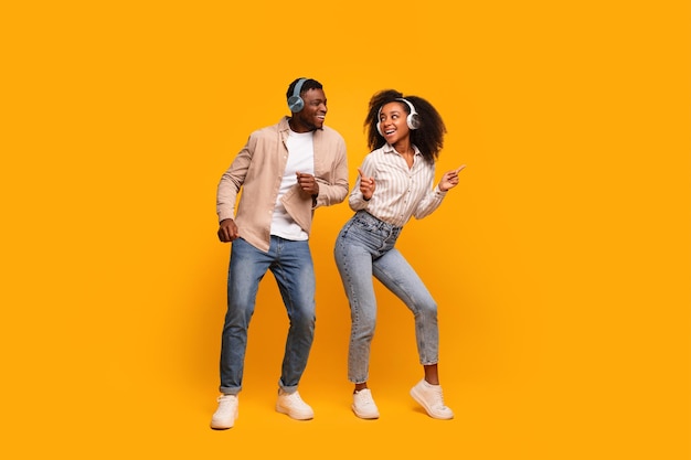 Dancing couple with headphones on yellow background