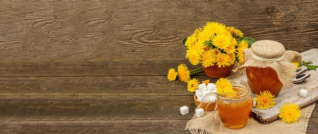 Dandelion jam or honey in the glass jar with a bouquet of fresh blooming dandelion flowers