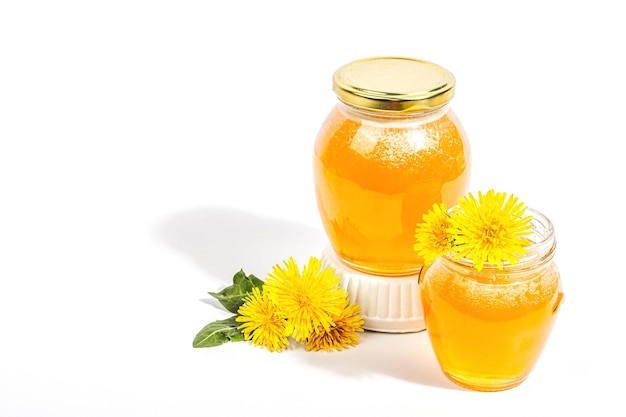 Dandelion jam or honey in the glass jar with fresh dandelion flowers isolated on white background