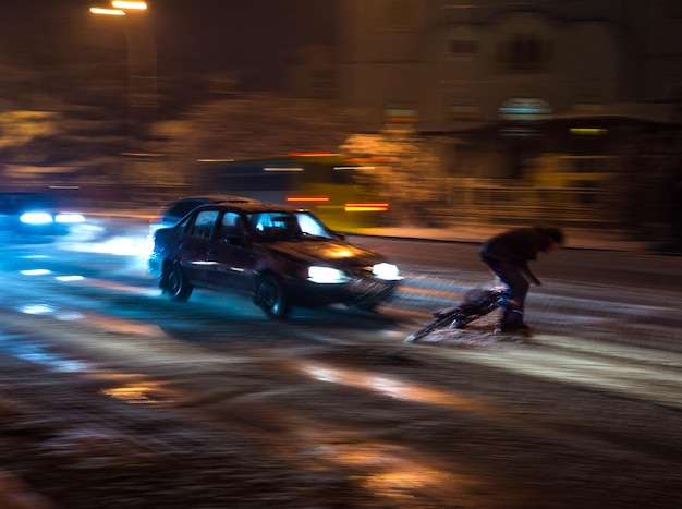 Dangerous city traffic situation with cyclist and car in the city at night in motion blur