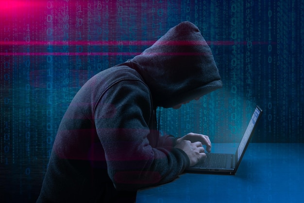 Dangerous Hooded Hacker Breaks into Government Data Servers Cybersecurity computer hacker with hoodie Hideout Place has Dark Atmosphere Hacking and malware concept