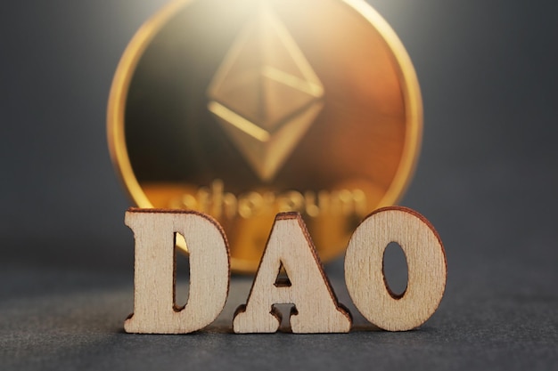 DAO Decentralized Autonomous Organization Letter DAO gold coin cryptocurrency Ethereum on grey background