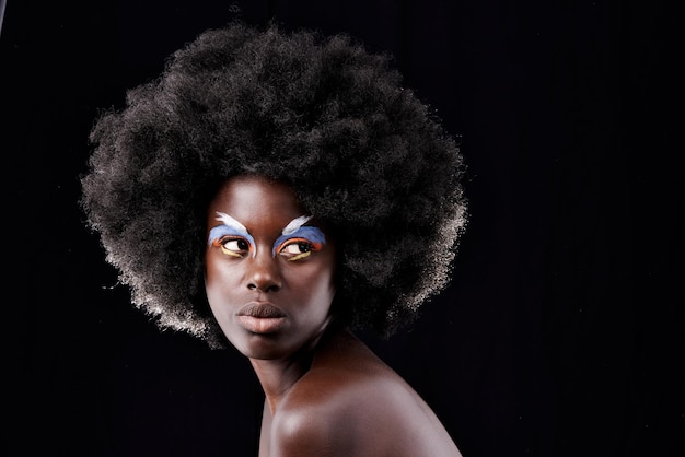 Daringly different Studio shot of a beautiful young model wearing colorful eye makeup posing against a black background