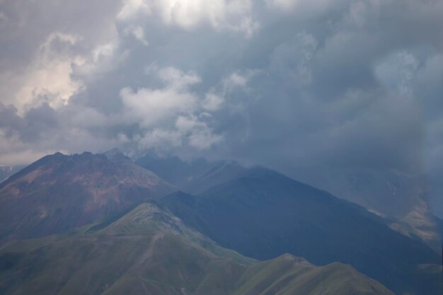 Dark atmospheric surreal landscape with a dark rocky mountain peak in low clouds