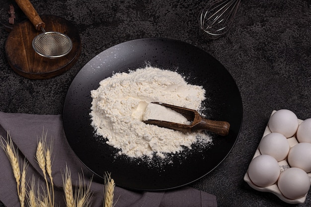 Dark background for baking with eggs, flour, wheat, whisk