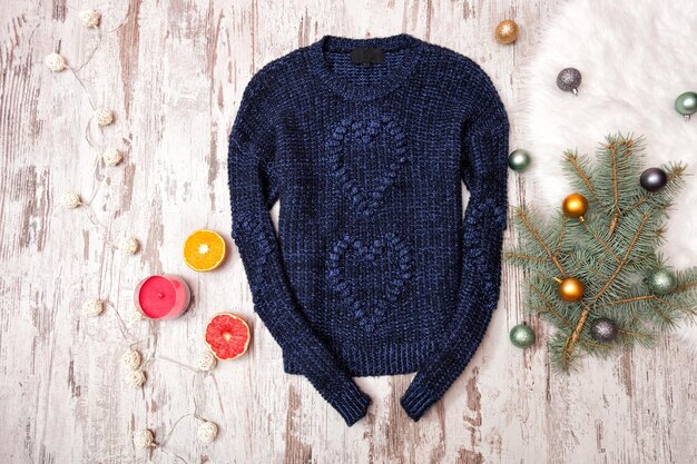 Dark blue knitted sweater on a wooden background Firtree branch with Christmas decorations