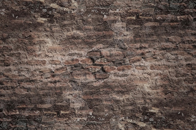 Dark brick structural ancient wall with destroyed stucco