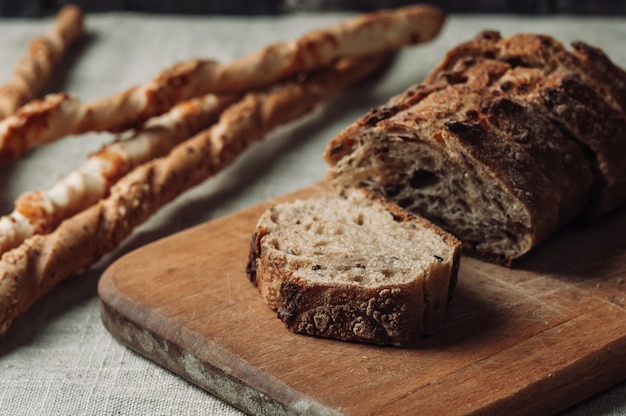  dark buckwheat bread  and Italian grissini are on the table.