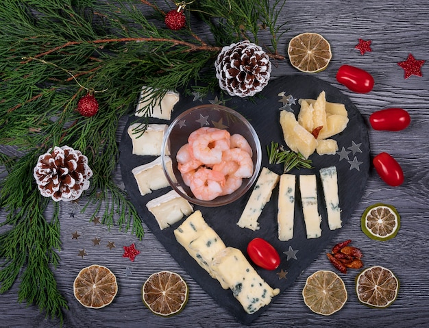 A dark cheese platter set with harissa and prawn, parmesan, gorgonzola, rosemary, olive and biscuits