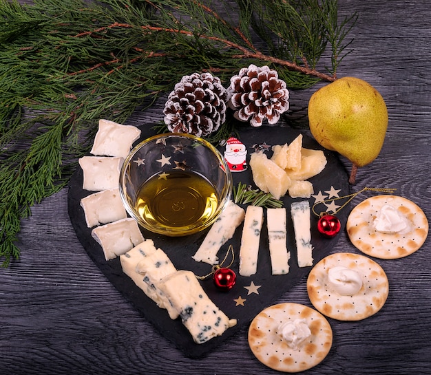 A dark cheese platter set with honey and pear, parmesan cheese, gorgonzola and biscuits