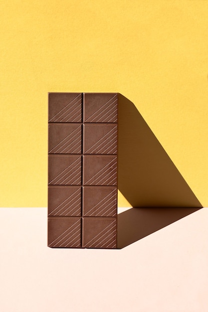 Photo dark chocolate bar with heavy shadows on colorful background