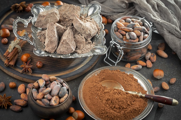 Dark chocolate in a composition with cocoa beans and nuts, on an old background.