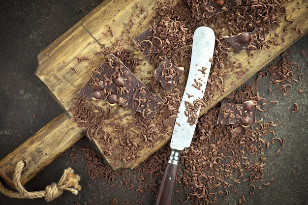 Dark chocolate in a composition with cocoa beans and nuts, on an old background.