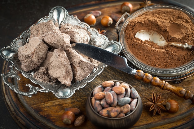 Dark chocolate in a composition with cocoa beans and nuts, on an old background.