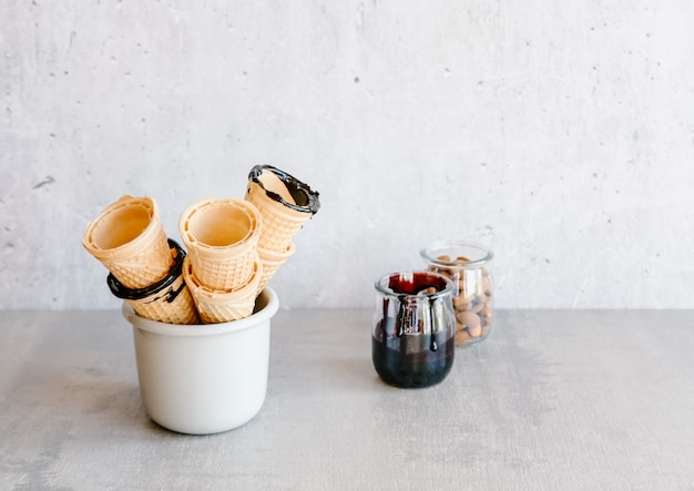 Dark chocolate sauce in a jar near icecream cones