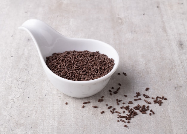 Dark chocolate sprinkles in a white bowl. Typical brazilian brigadeiro topping.