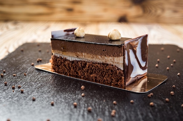 Dark chocolate vegan cake with candies and nuts on wooden background