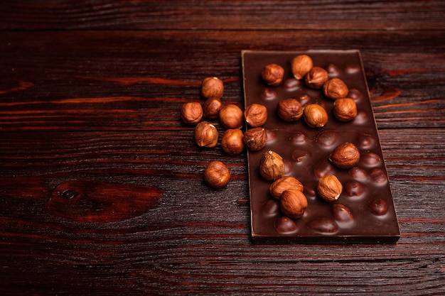 Dark chocolate with hazelnuts on wooden table