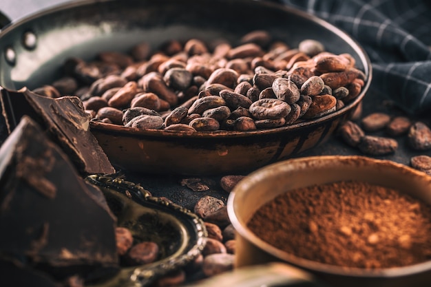 Dark chokolate cocoa beans and powder on concrete table.