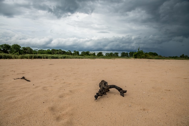 Dark clouds and precipitation from a thunderstorm over sand dune in Moon river, rural Surin, Thailand