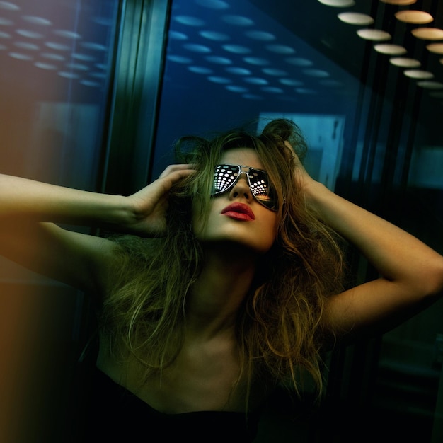 dark color toned picture of fashionable woman in nightclub