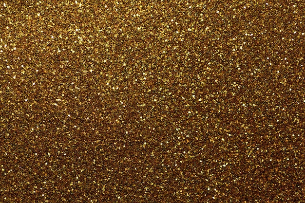 Dark golden sparkling background from small sequins, closeup. Brilliant backdrop.