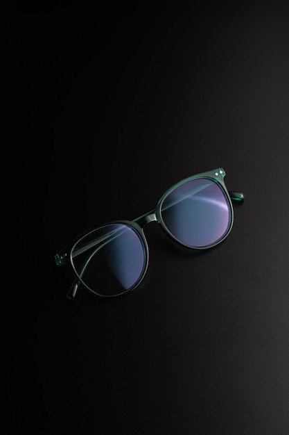 Dark green eyewear with dark background and dramatic shadow effect