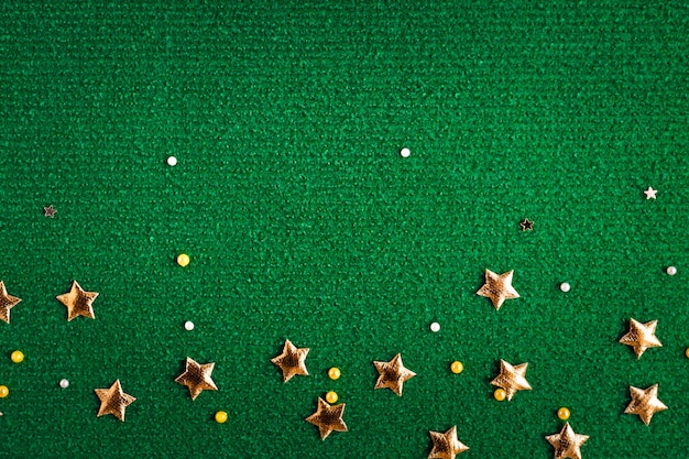 Dark green textile background with gold glittering stars and ribbons top view