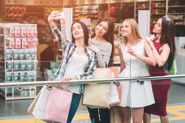 Dark-haired girl in pants is taking picture of herself with friends