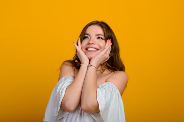 Dark-haired young woman with a smile and big suprised eyes posing.