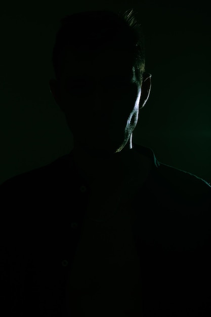 Dark intimidating silhouette of a brutal man in a black room