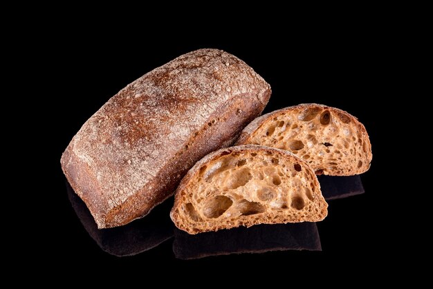 Dark Italian ciabatta sliced bread. Freshly baked homemade bread isolated on black. Healthy eating and traditional bakery, baking bread concept.