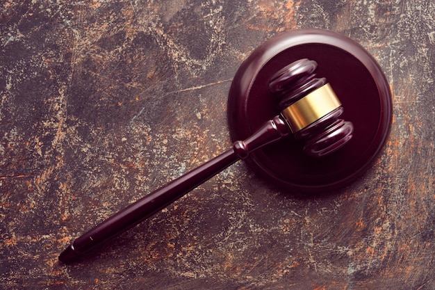 Dark polished wooden law hammer or gavel on wooden table