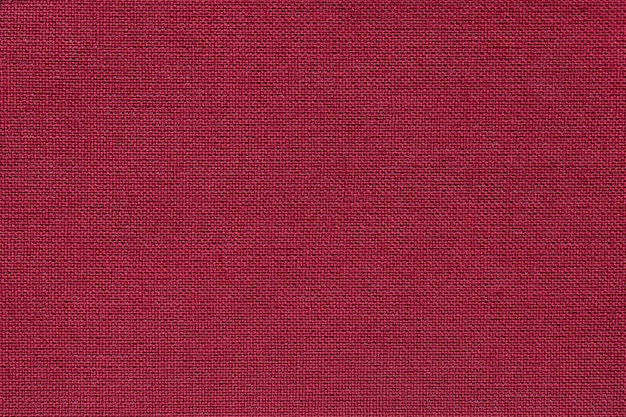 Dark red background from a textile material with wicker pattern, closeup.