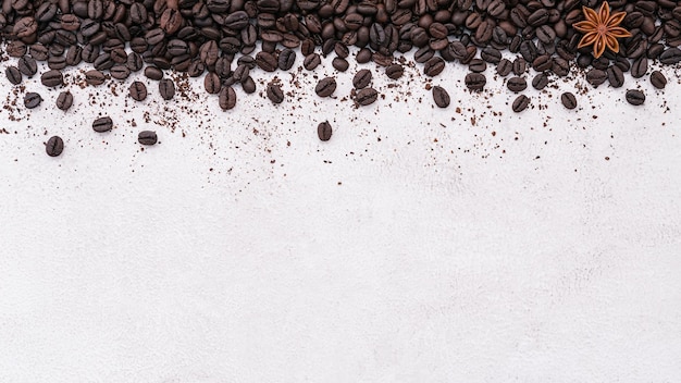 Dark roasted coffee beans setup on white concrete background with copy space