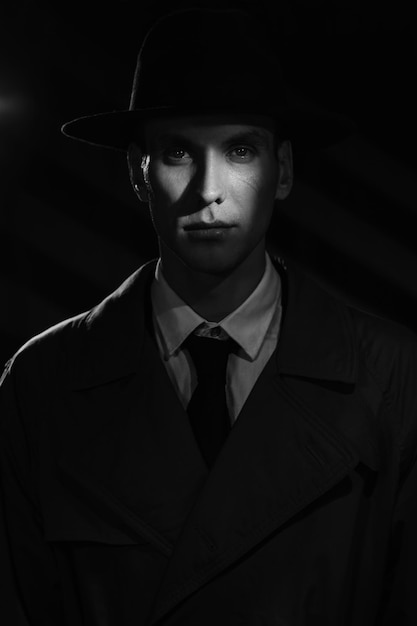 A dark silhouette of a dangerous man in a hat The style of film noir Private detective spy investigation concept Dramatic light